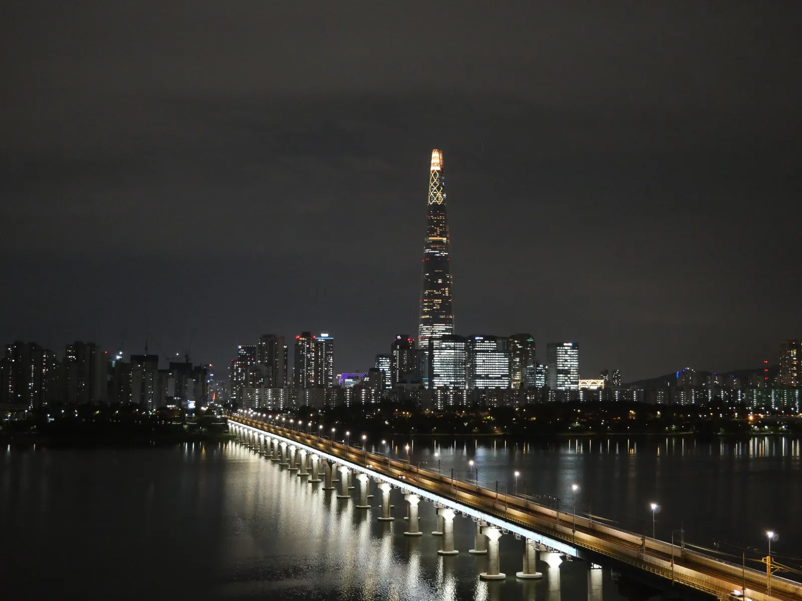 The lit tower and lake at the Lotte World complex in Seoul at night, South Korea