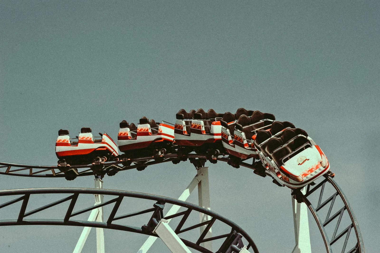 A roller coaster train cresting a loop against a pale sky in South Korea