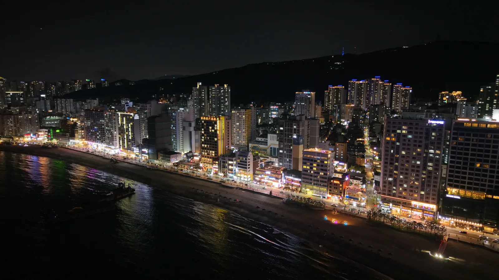The lit beachfront and buildings of a Busan beach at night, South Korea