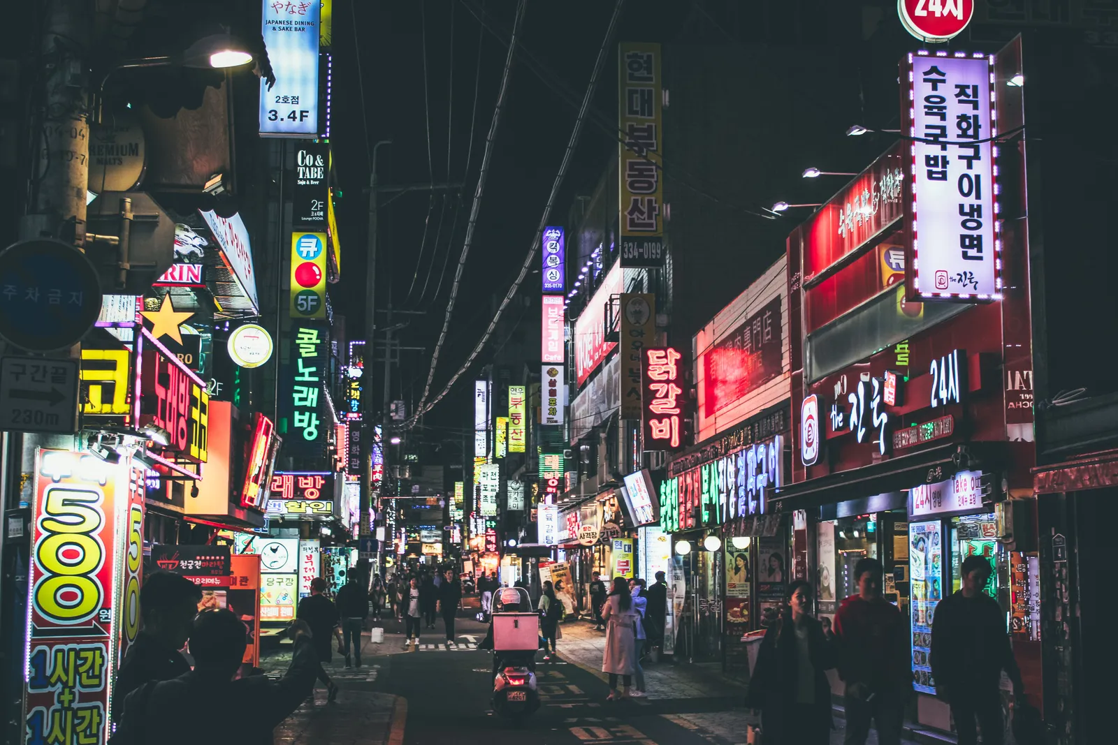 A neon-lit street of bars and shops at night in Hongdae, Seoul, South Korea