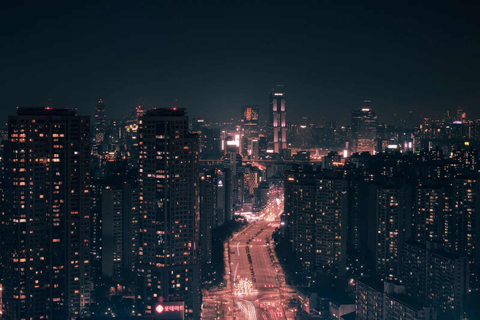 Tower blocks lit up at night above a road with a river of car headlights, Seoul, South Korea