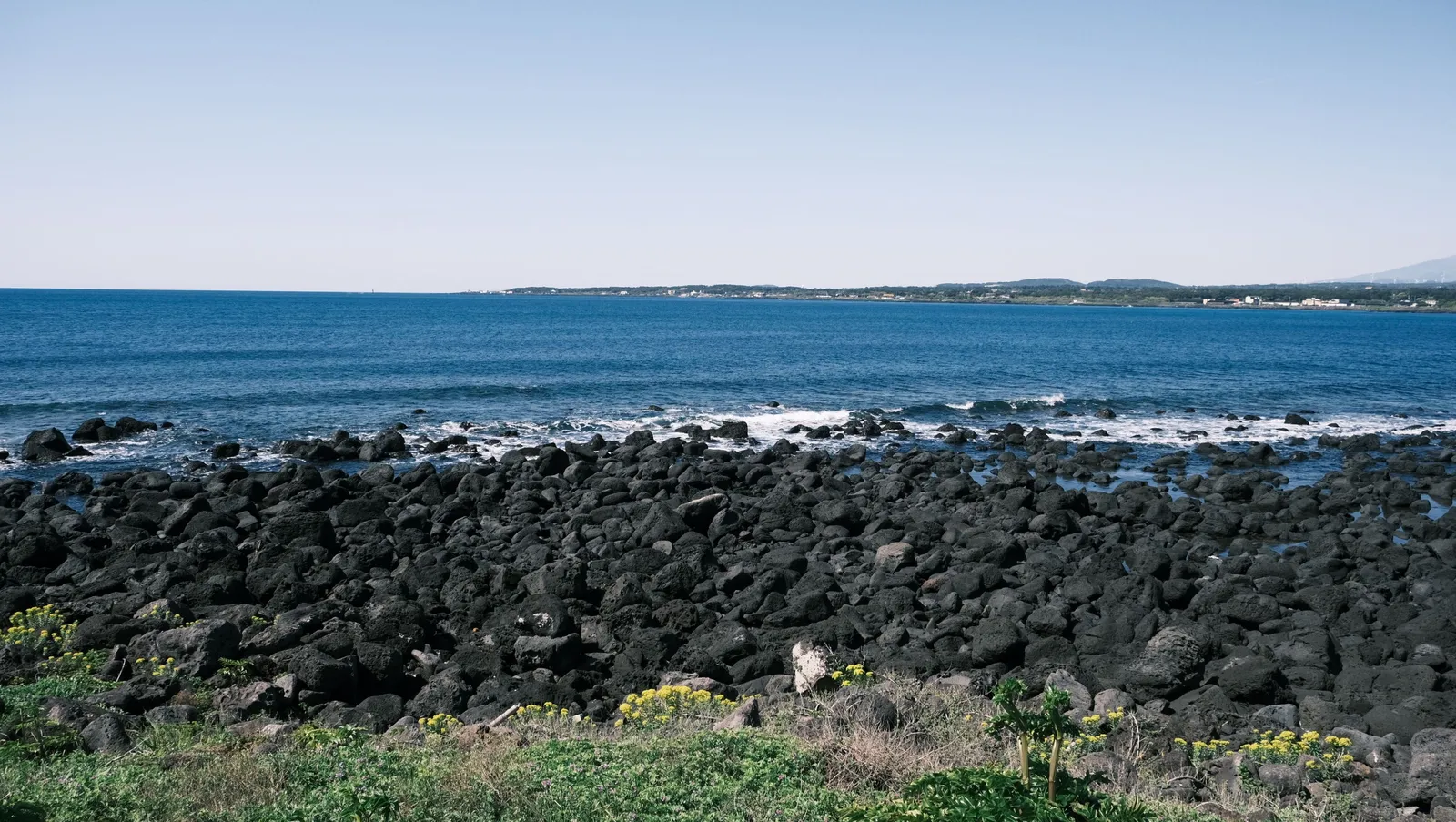 A rocky volcanic coastline with black basalt boulders on Jeju island, South Korea