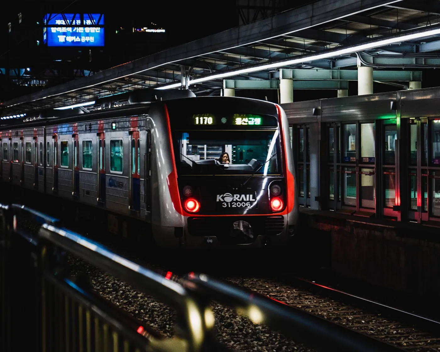 A Korail train at a brightly lit station platform in Seoul at night, South Korea