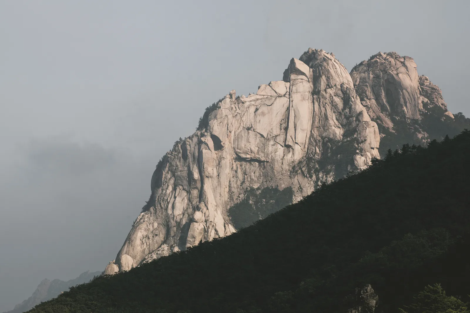 Hikers on a granite ridge trail with forested mountains behind in South Korea