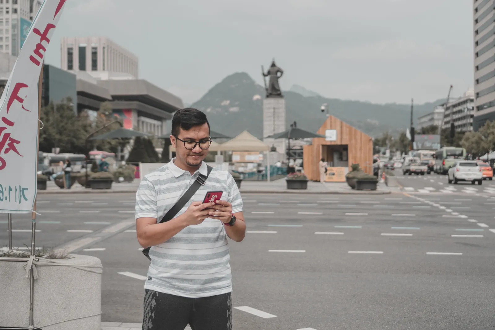A tourist checking a smartphone map app on a busy street in Seoul, South Korea