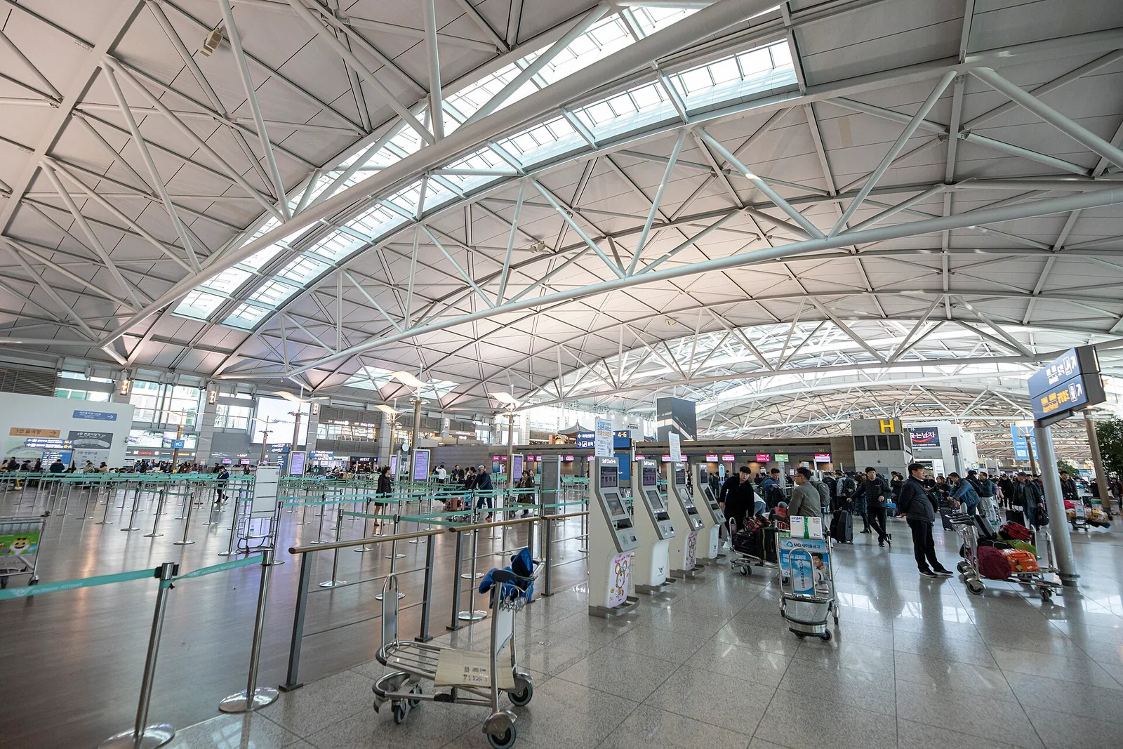 The vaulted departures hall of Incheon International Airport with travellers and trolleys, South Korea