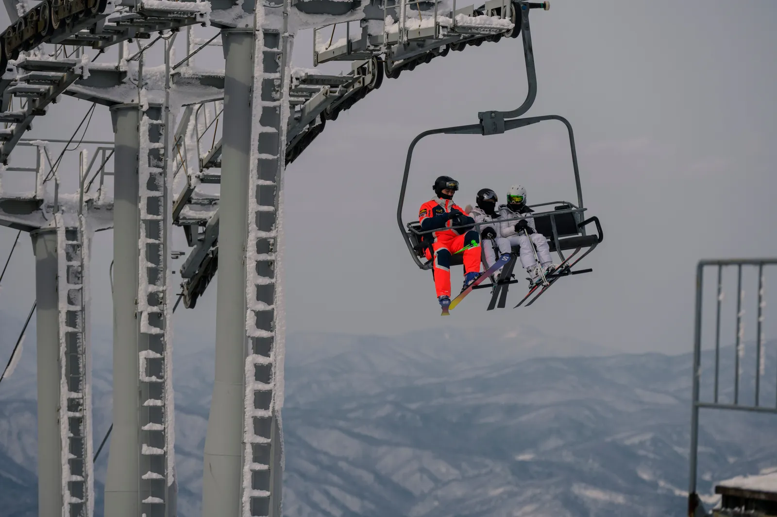 A chairlift carrying skiers above a snow covered slope in South Korea
