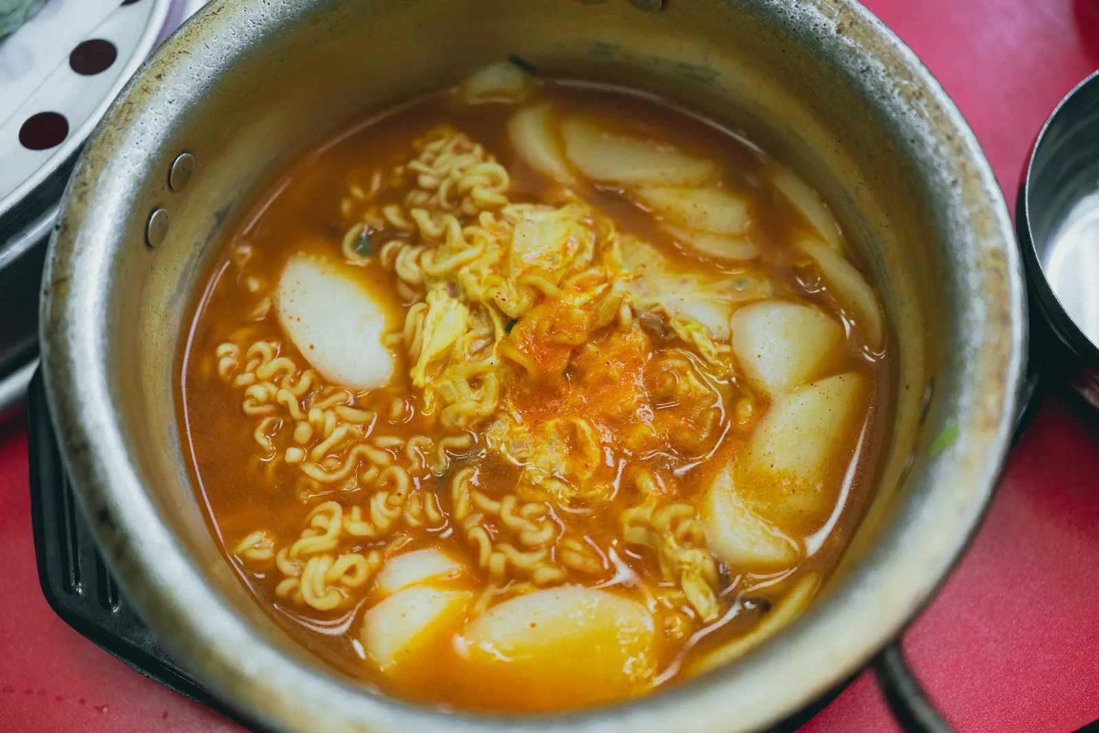 A street-food market stall serving spicy tteokbokki rice cakes and fried snacks to customers in South Korea