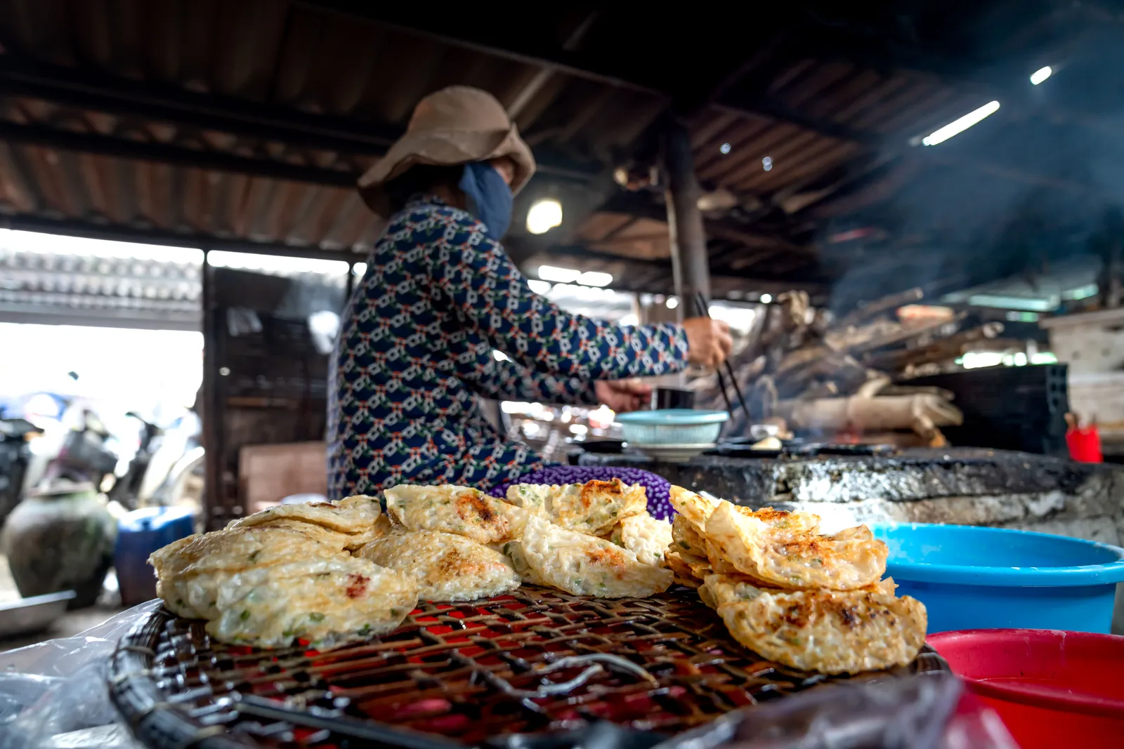 A vendor frying a savoury Korean pancake on a large flat pan at a street food stall, South Korea