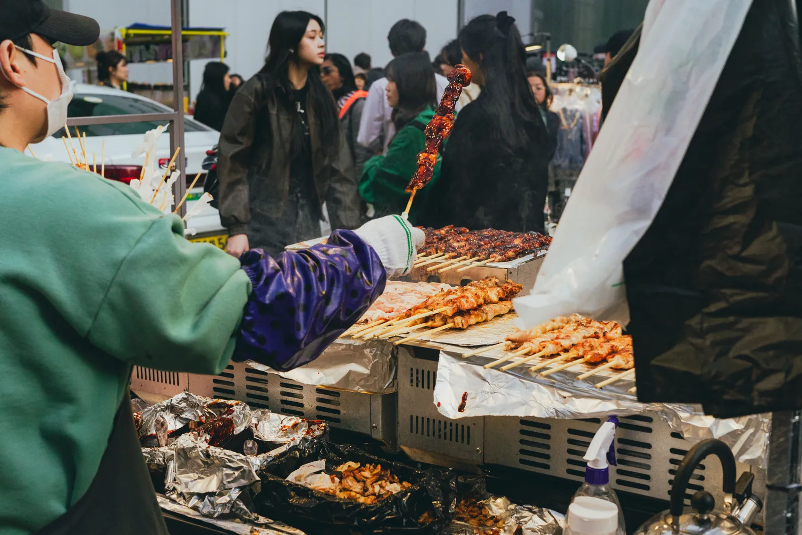 Skewered street food snacks displayed at a busy night market stall in a South Korean city