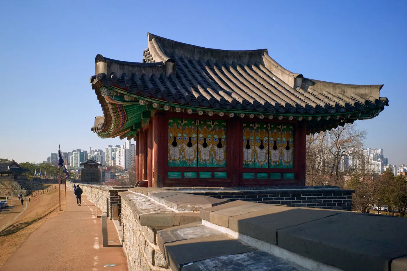 A traditional Korean pavilion on an old city fortress wall with the modern city behind