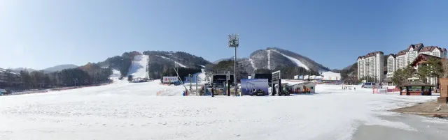 Snowy ski slopes with lifts and base buildings at the foot of the mountain