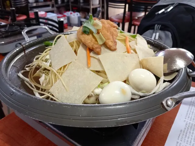 A metal pot with rice cakes in red sauce, boiled eggs and thin slices