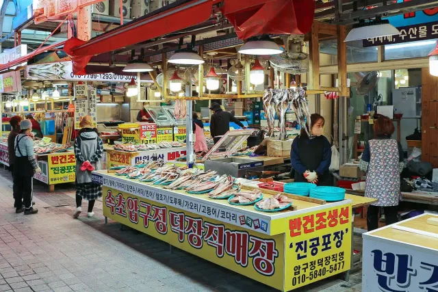 Covered market stalls piled with dried fish and shoppers in the alley