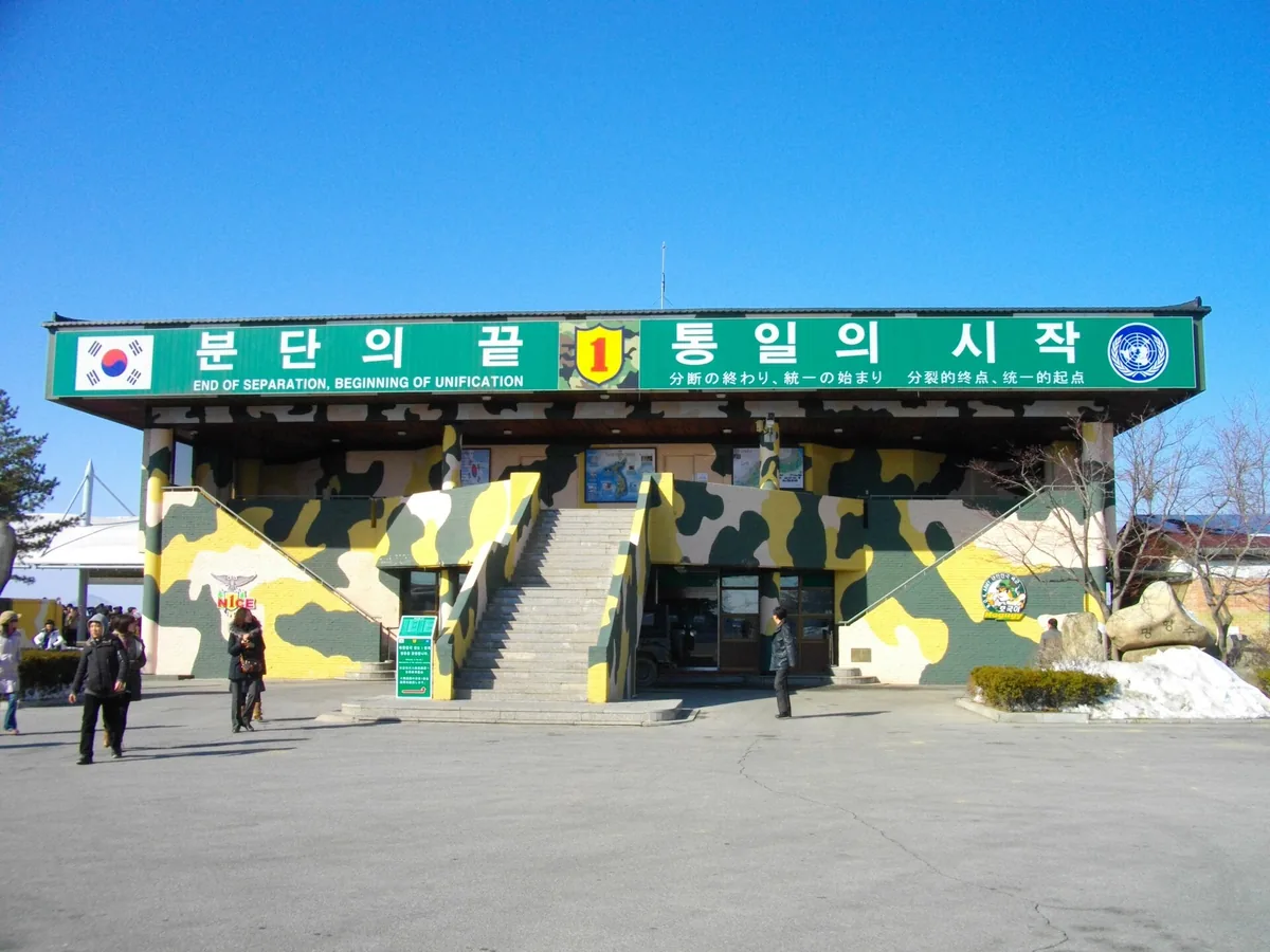 An observatory building painted in military camouflage with a large green banner above the entrance, under a blue sky