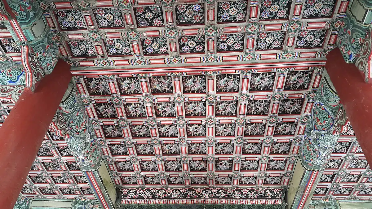 Painted wooden ceiling panels in red and green with flower and animal motifs between red pillars
