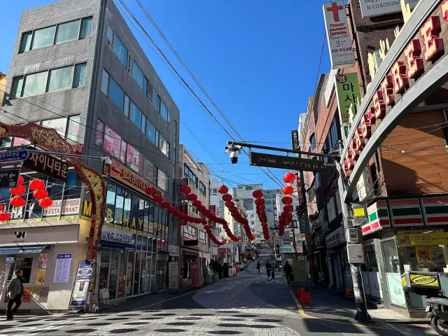 A city street with red lanterns strung above the shopfronts
