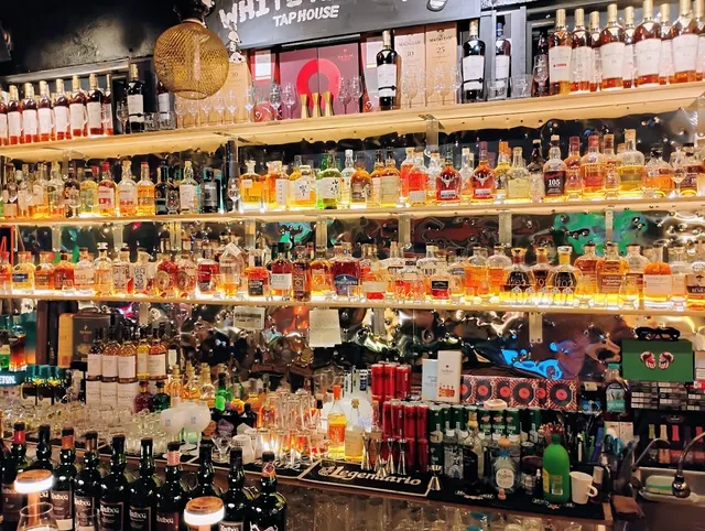 A wall of shelves packed with spirit bottles behind the bar counter