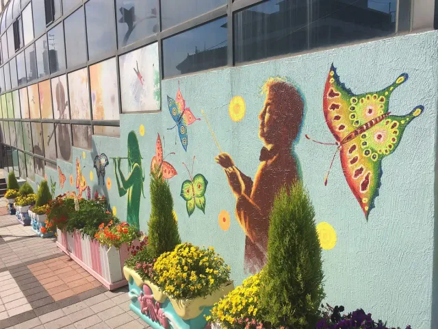 A street wall painted with a girl and large colourful butterflies