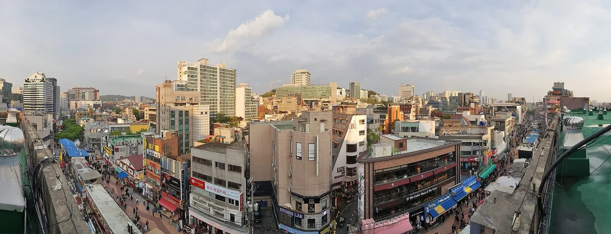 An elevated view over a dense city district with colourful shopfronts and pedestrian streets