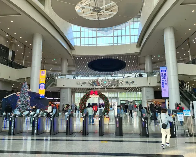 A tall entrance hall with a glass dome, ticket gates and visitors in the lobby