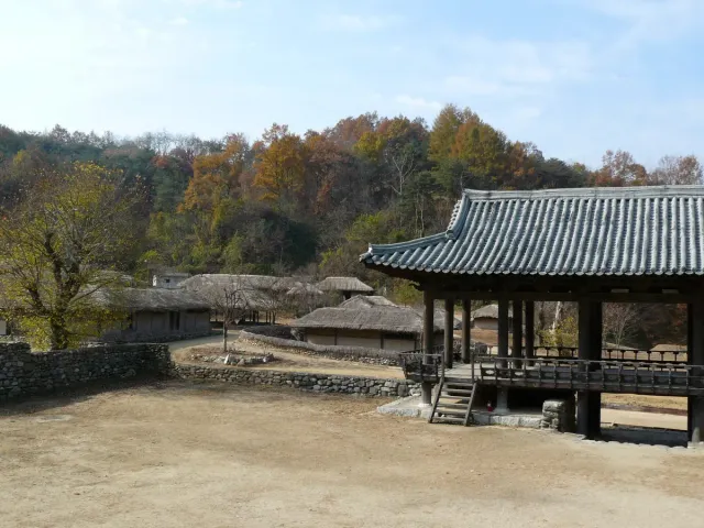 A traditional tiled roof above a wide river bank and bare trees