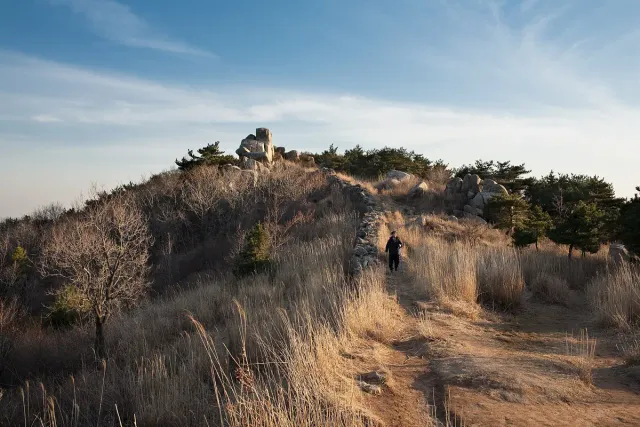 An old stone wall winding along a mountain ridge covered in dry grass