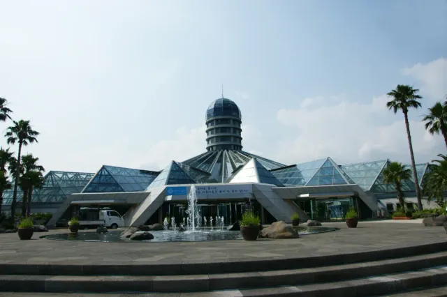 A glazed greenhouse building with a central dome, surrounded by palms