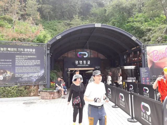 An arched tunnel mouth in a hillside with visitors at the entrance