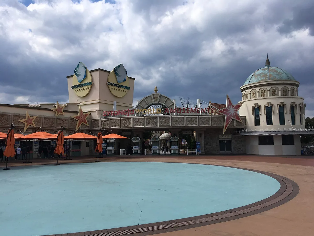 Amusement park entrance with golden stars, a domed rotunda and a wide shallow pool in front