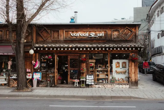 A traditional wooden front with a tiled eave, items displayed in the windows and a bare tree in the street