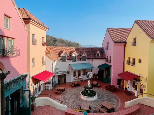 A paved courtyard with a small fountain surrounded by colorful houses with tiled roofs