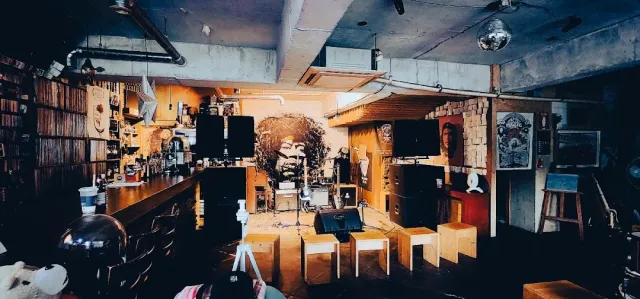 A bar with a small stage, a drum kit and a wall painting of a guitar player