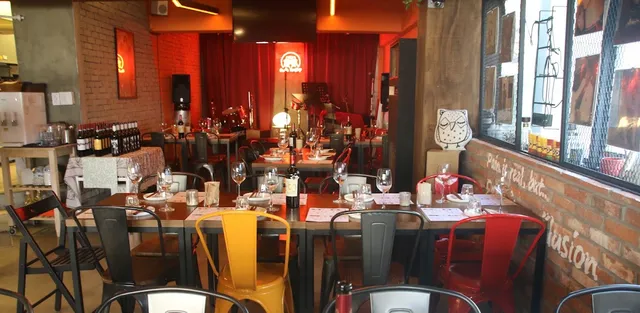 A space with brick walls, colorful metal chairs and a stage with red curtains