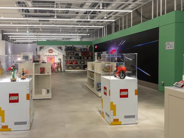Glass display cases with colorful brick models in a wide store space and a green wall