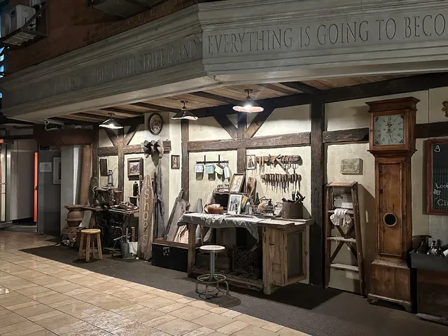 A facade designed as an old workshop with a grandfather clock, tools and a wooden table