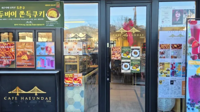 An entrance with a glass door covered in posters, and beside it a sign showing a bridge illustration