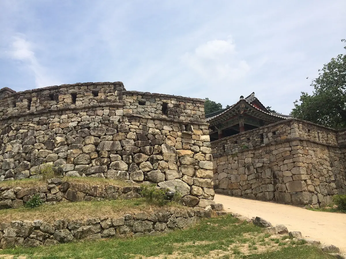 Ancient rough stone rampart beside a gateway topped with a traditional tiled roof