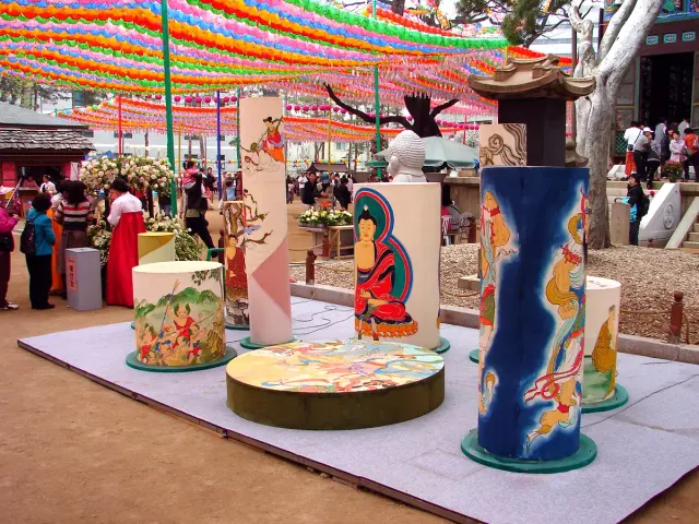 Colourful paper lanterns strung above a temple courtyard with painted lantern pillars
