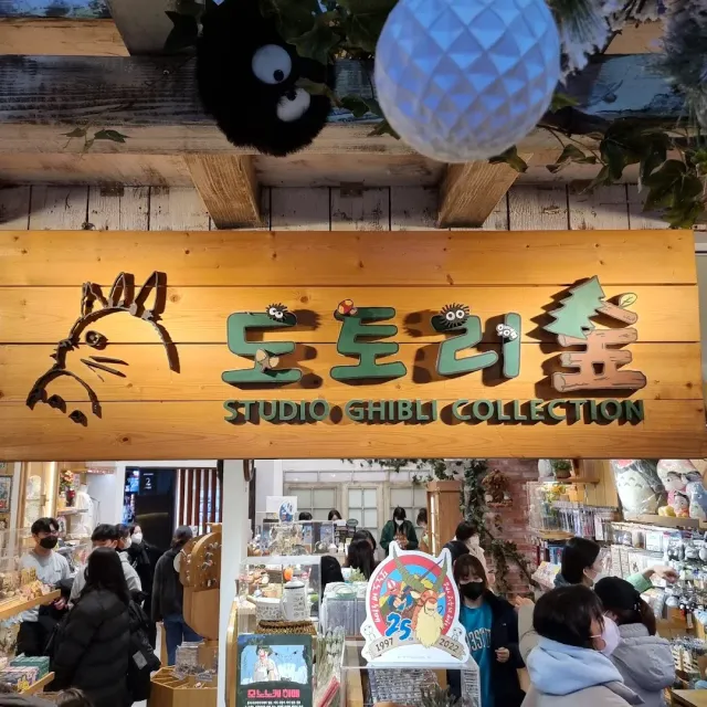 A carved wooden sign above a crowded souvenir shop and visitors among the shelves
