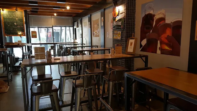 High bar tables with metal stools, and a large poster of beer glasses on the wall