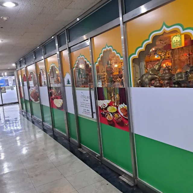 A corridor with a display window in green and yellow arches, metal vessels and photos of dishes