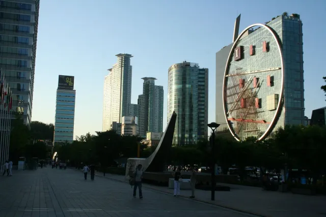A city plaza with a giant ring sculpture and office towers around it