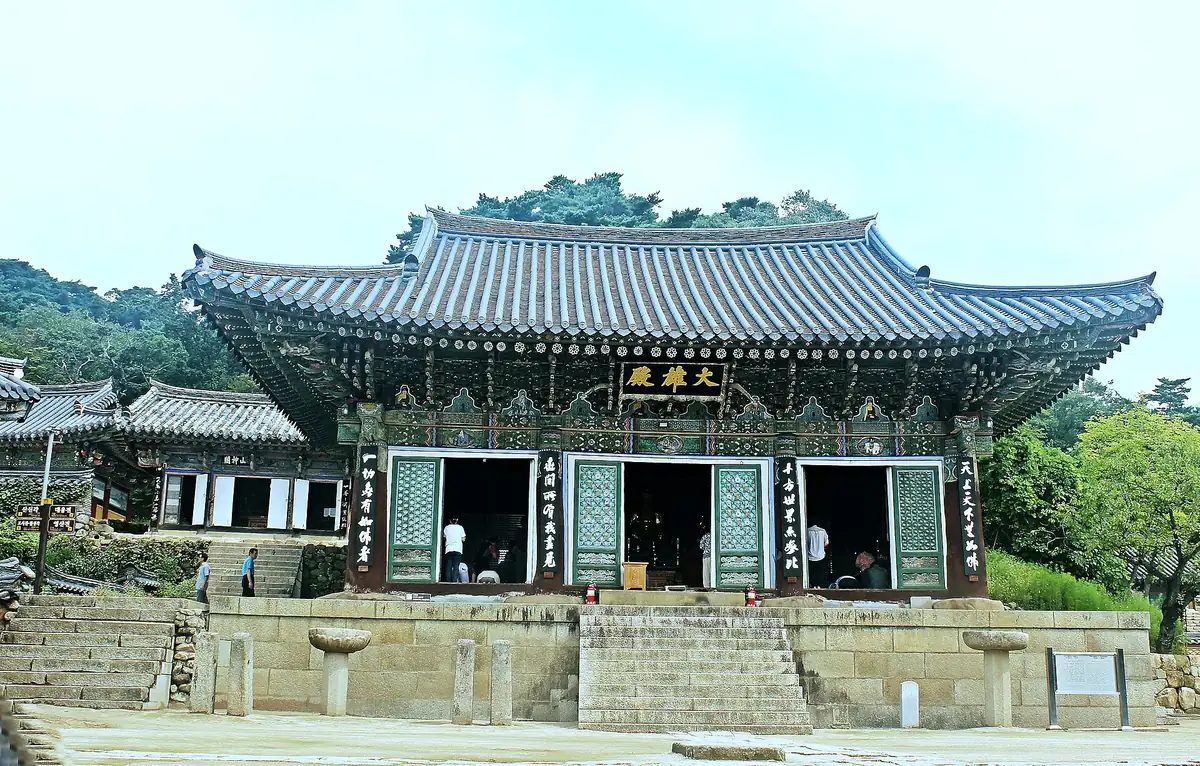 Temple hall with a double tiled roof and carved wooden doors above broad stone steps