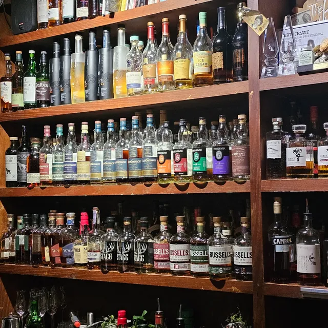 Wooden shelves packed with whisky and spirit bottles, in warm lighting