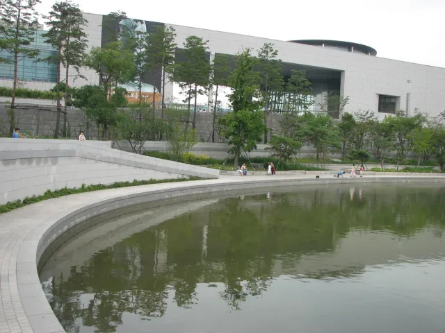 A long low museum building across a large reflecting pool