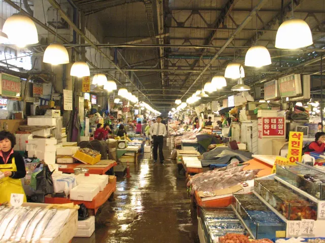 A long market hall of fish stalls and water tanks under hanging lamps