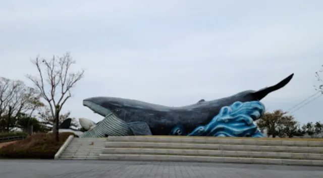 A giant whale sculpture on painted waves above wide stone steps
