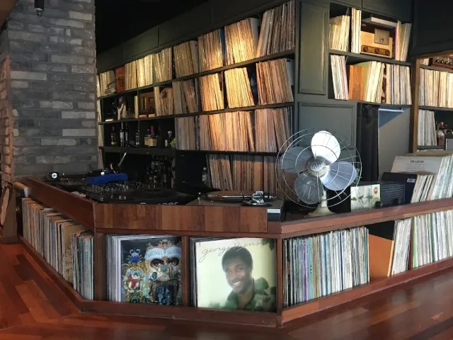 A counter packed with records, walls of shelved albums, a turntable and an old fan