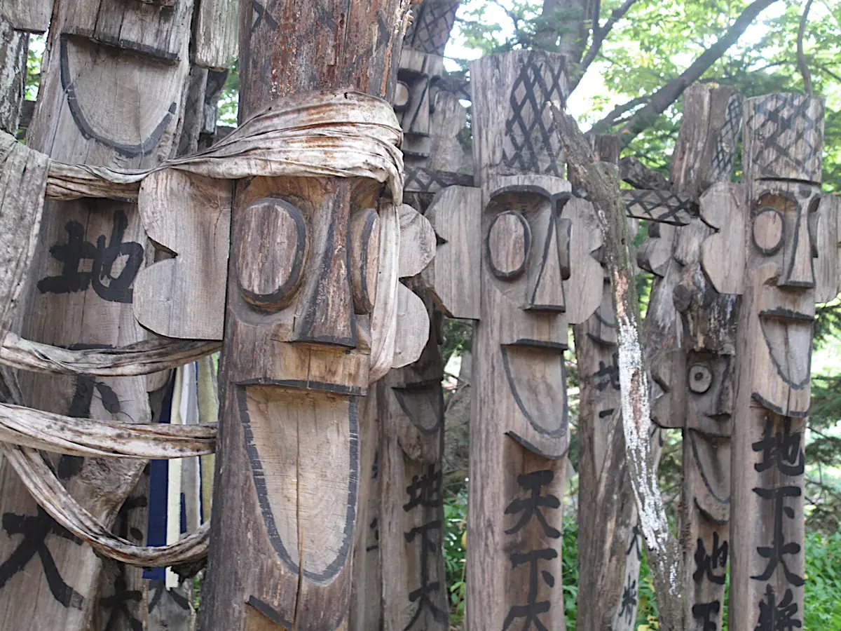 Carved wooden guardian posts with bulging eyes and black brush script down their trunks